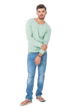 good-looking young man with beard posing with his hands in his pockets in jeans and sandals isolated on white background
