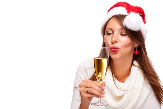 Attractive woman with red Santa hat holds a glass of champagne in her hand and smiles isolated on white background freeing text space