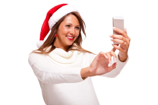 Attractive woman with red Santa hat reads a text message on her phone smartphone and sends Christmas wishes smiling with joy isolated on white with text-free free-space