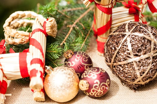Decoration for Christmas with red and gold Christmas tree balls in front of green fir branches in the background