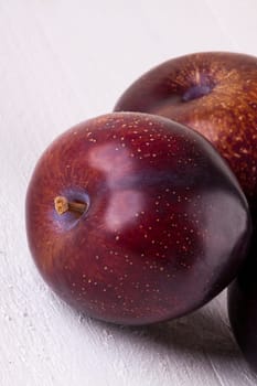 Fresh shiny juicy plums with ripe color with stem up as close-up