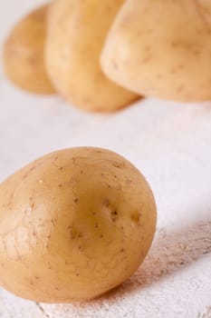 Fresh washed potatoes with peel as a close-up on a rustic wooden board