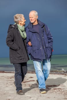 older adult happy couple walks on the beach in autumn lifestyle happiness