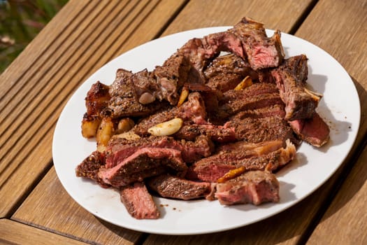 Sliced medium pink cooked beef on a plate with napkin on a wood base