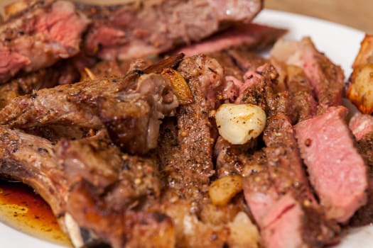 Sliced medium pink cooked beef on a plate with napkin on a wood base
