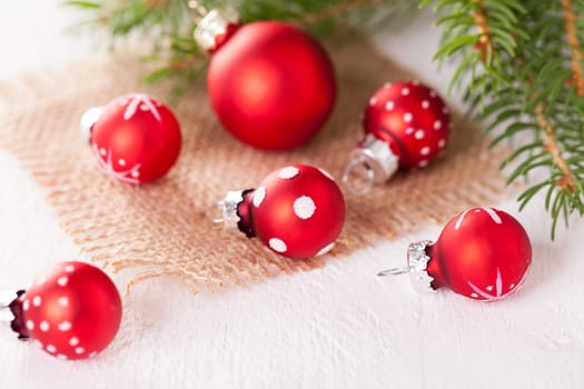 Beautiful red Christmas balls with small white dots with green fir branches on a jute sack