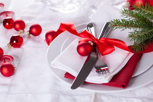 Romantic Christmas table with red balls and red bow with cutlery knife and fork on a napkin
