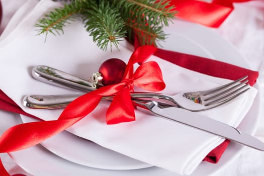 Romantic Christmas table with red balls and red bow with cutlery knife and fork on a napkin