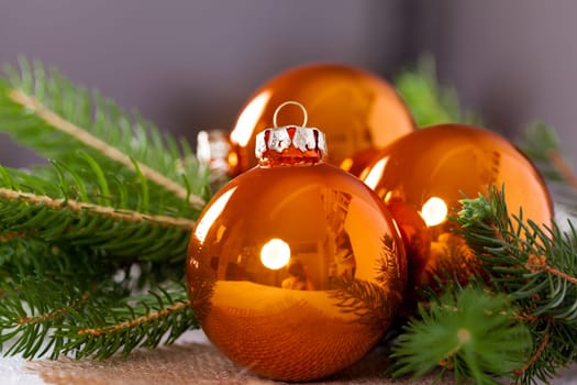 Shiny orange glass balls Christmas balls with green twigs on a jute sack as a close-up