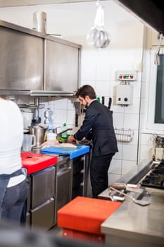 young adult chef in the restaurant kitchen while cooking at the herd preparation