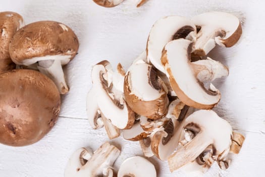 Fresh stone mushrooms Champiggnons whole and sliced on a white wooden board