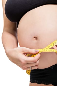 Pregnant woman with a measuring tape measures her girth on her abdomen isolated against a white background