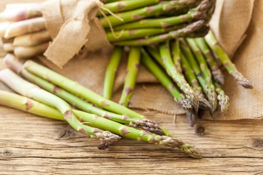 Fresh healthy green asparagus as a close-up on a wooden table in sunlight