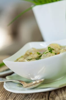 Bowl with Russian Pelmeni Italian tortellini with broth and parsley close-up on a wooden table