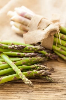 Fresh healthy green asparagus as a close-up on a wooden table in sunlight
