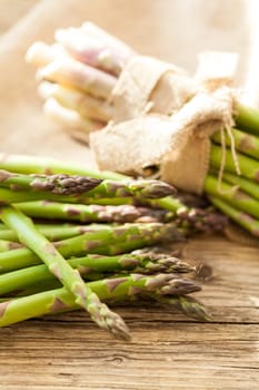Fresh healthy green asparagus as a close-up on a wooden table in sunlight