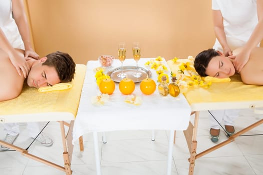 Relaxed young couple receiving shoulder massage at beauty spa