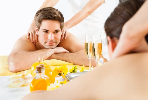 Happy man looking at woman while receiving shoulder massage in beauty spa