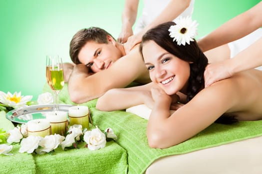 Portrait of smiling young couple receiving shoulder massage at beauty spa