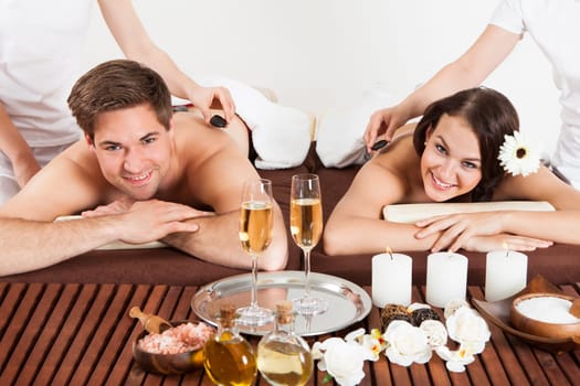 Portrait of happy young couple receiving shoulder massage at beauty spa