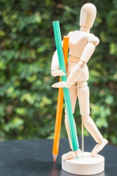 Wooden artist manikin standing with colour pencil, stock photo