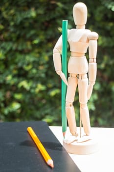 Wood artist mannequin standing with colour pencil, stock photo