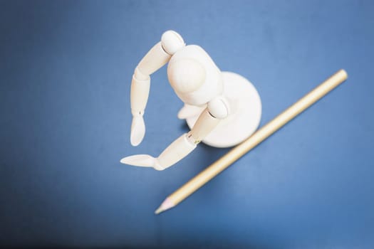 Wooden mannequin and pencil on dark background, stock photo