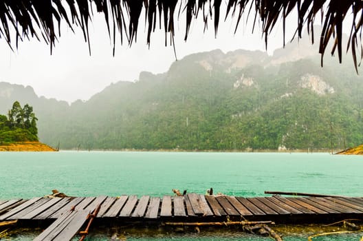 Mountain and river front of the hut while it was raining in Ratchaprapha Dam at Khao Sok National Park, Surat Thani Province, Thailand.