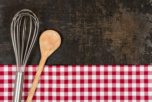 Old baking tray with red checkered tablecloth and baking utensils