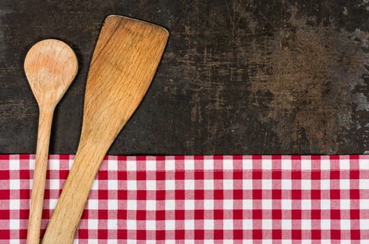 Old baking tray with red checkered tablecloth and cooking utensils