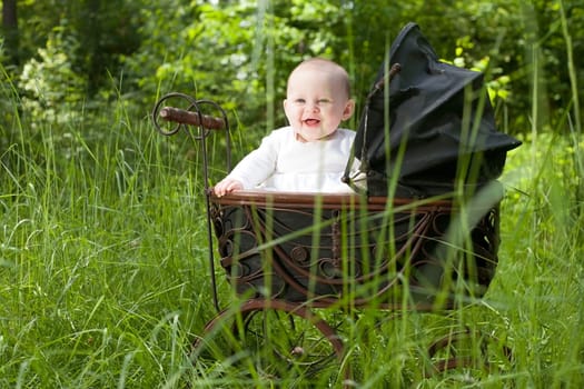 Baby girl is sitting in a vintage pram