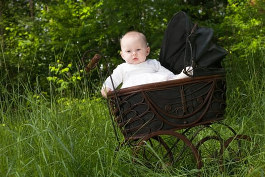 Baby girl is sitting in a vintage pram