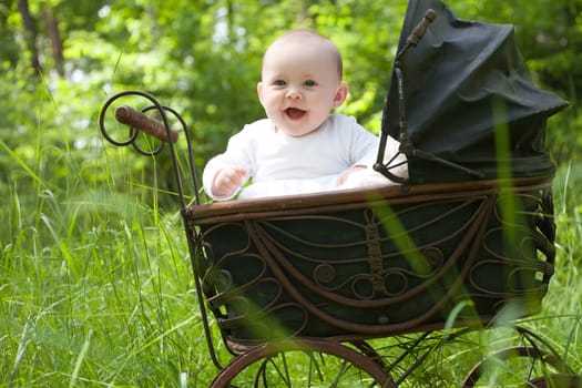 Baby girl is sitting in a vintage pram