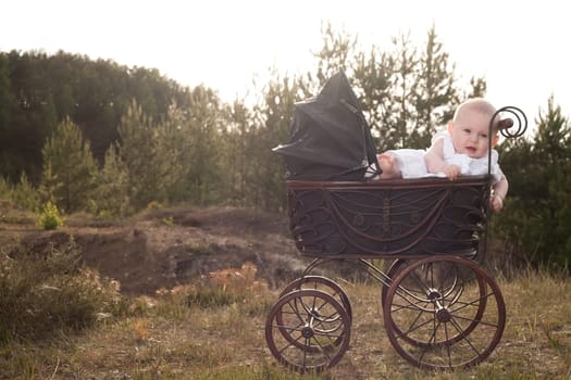 Baby girl is sitting in a vintage pram