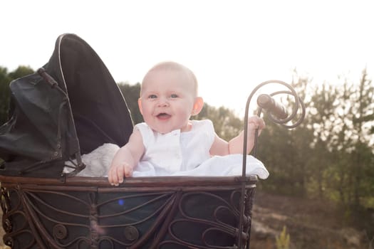 Baby girl is sitting in a vintage pram