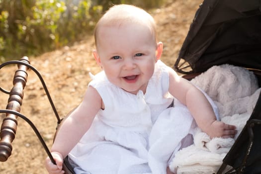 Baby girl is sitting in a vintage pram