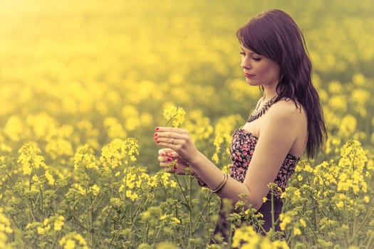 Attractive genuine young girl enjoying the warm summer sun in a wide green and yellow meadow. Part of series.