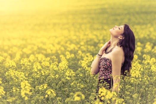 Attractive genuine young girl enjoying the warm summer sun in a wide green and yellow meadow. Part of series.
