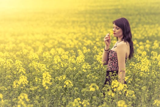 Attractive genuine young girl enjoying the warm summer sun in a wide green and yellow meadow. Part of series.