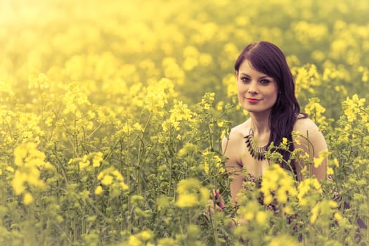 Attractive genuine young girl enjoying the warm summer sun in a wide green and yellow meadow. Part of series.