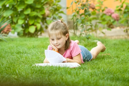 Girl reading a book in the park laid down on the grass