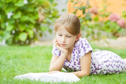 Girl reading a book in the park laid down on the grass
