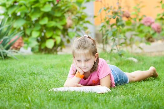 Girl reading a book in the park laid down on the grass