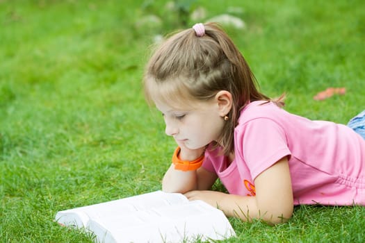Girl reading a book in the park laid down on the grass