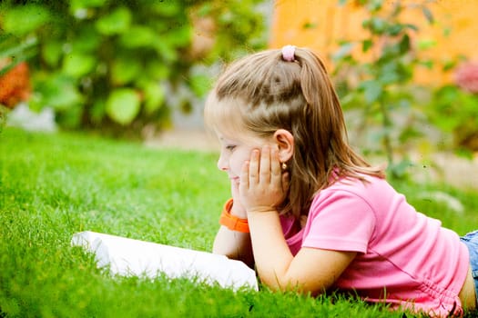 Girl reading a book in the park laid down on the grass