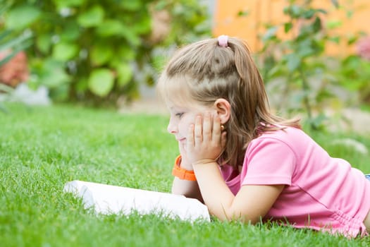 Girl reading a book in the park laid down on the grass