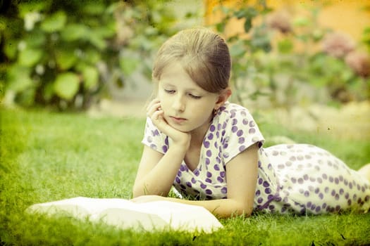 Girl reading a book in the park laid down on the grass