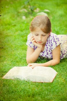 Girl reading a book in the park laid down on the grass