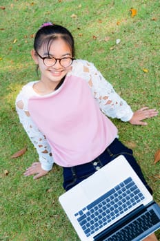 Cute girl is happy with notebook on grass in park