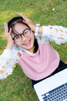 Cute girl is happy with notebook on grass in park
